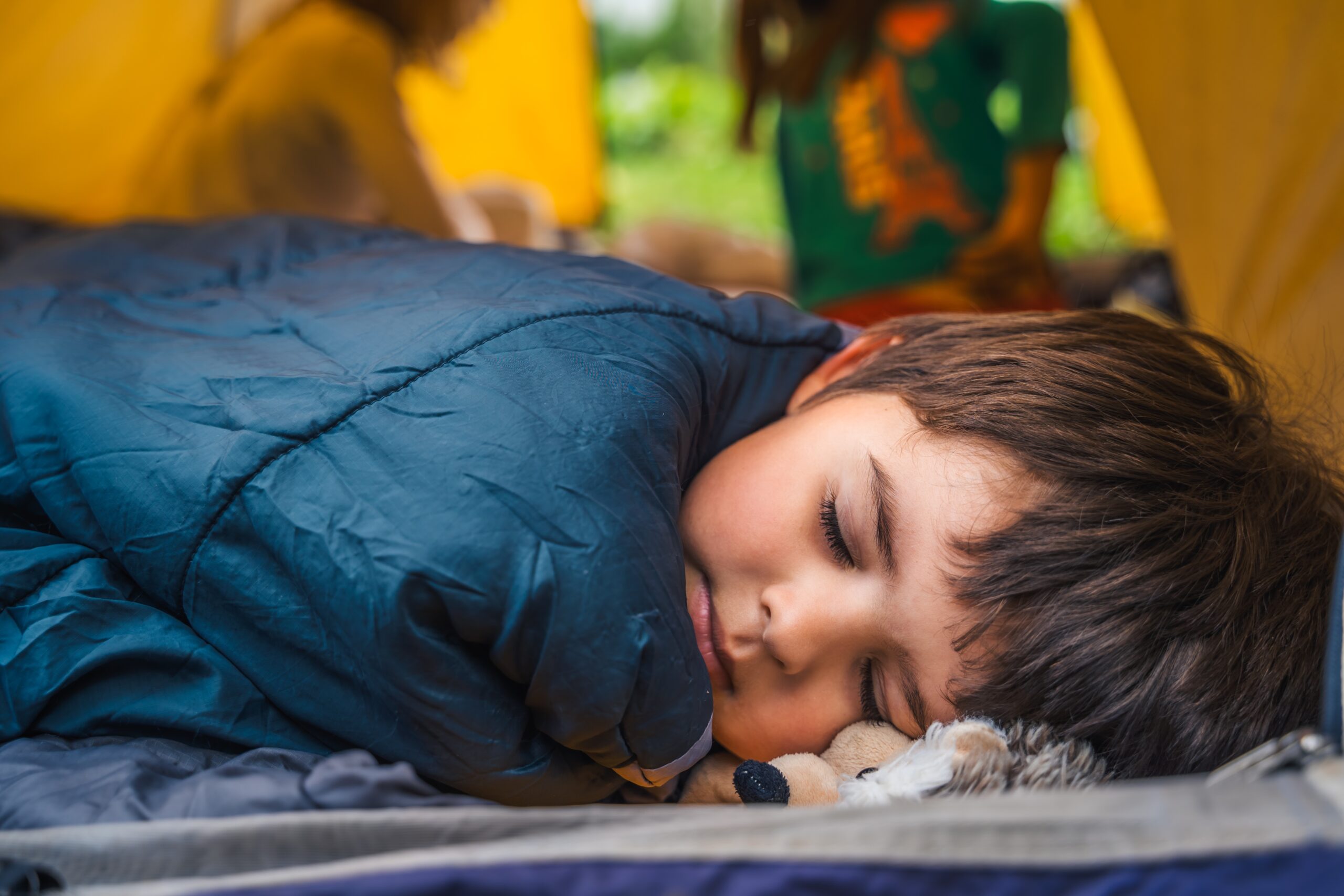 Small children, kids, boy play, sleep in sleepig bag in orange tourist tent. Family trip,hike to nature. Backyard games, having fun. Outdoor recreation,activity. Self-assembly,setting up camping tent.